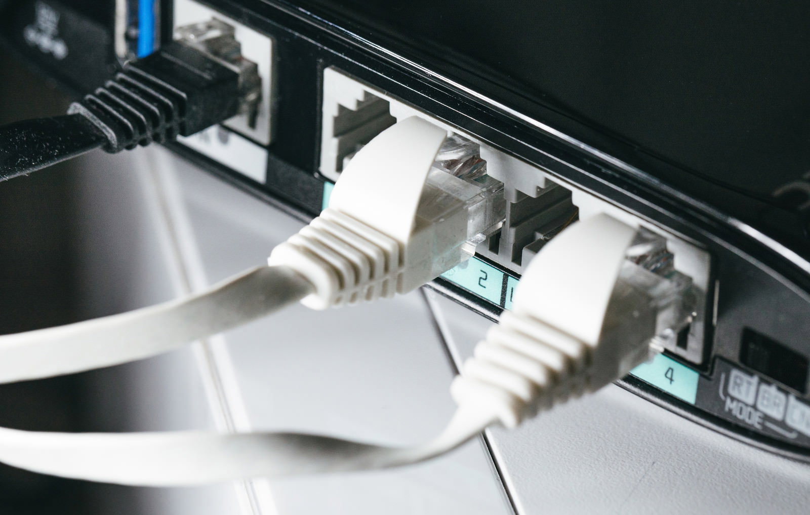 黒いルータに白いLANケーブルが複数接続されている