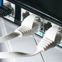 黒いルータに白いLANケーブルを複数接続の写真