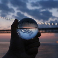 水晶玉の中に映り込む大橋と夕焼け空の風景の写真
