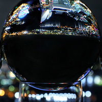 水晶玉に映り込む都会の夜景と周囲の光の写真