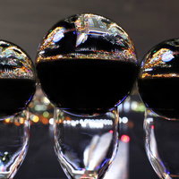 グラスの上に乗った水晶玉に映る都会の夜景の写真