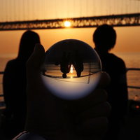 夕暮れの橋で寄り添う恋人と水晶玉に映る二人のシルエットの写真