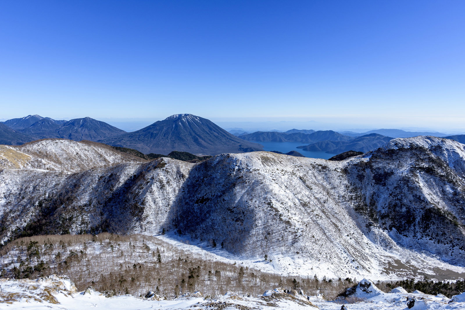 青空の下、雪に覆われた日光の山々が連なる冬景色
