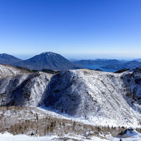 青空の下、雪化粧した男体山と中禅寺湖の冬山風景の写真