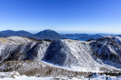 青空の下、雪化粧した男体山と中禅寺湖の冬山風景