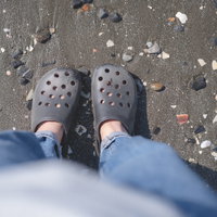 砂浜に立つサンダルを履いた女性の足元の写真