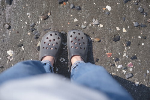 砂浜に立つサンダルを履いた女性の足元