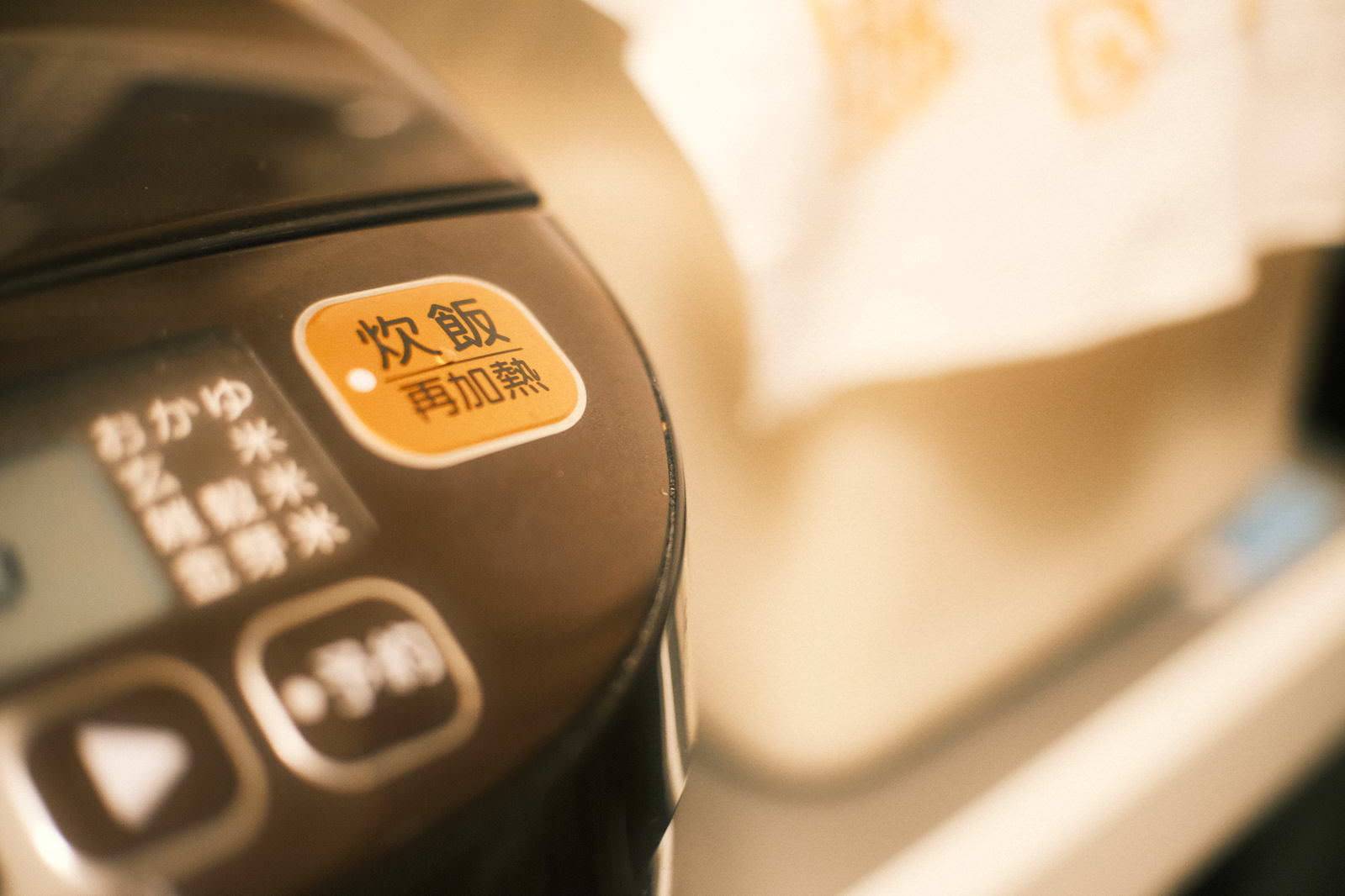 Orange-lit rice cooking button and control panel on an electric jar