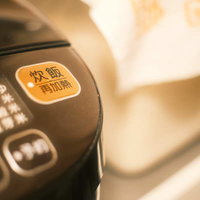 電子ジャーの黒いパネルに配置されたオレンジ色の炊飯ボタンの写真