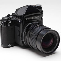 白い背景に置かれた黒いボディのPENTAX67中判フィルムカメラの写真