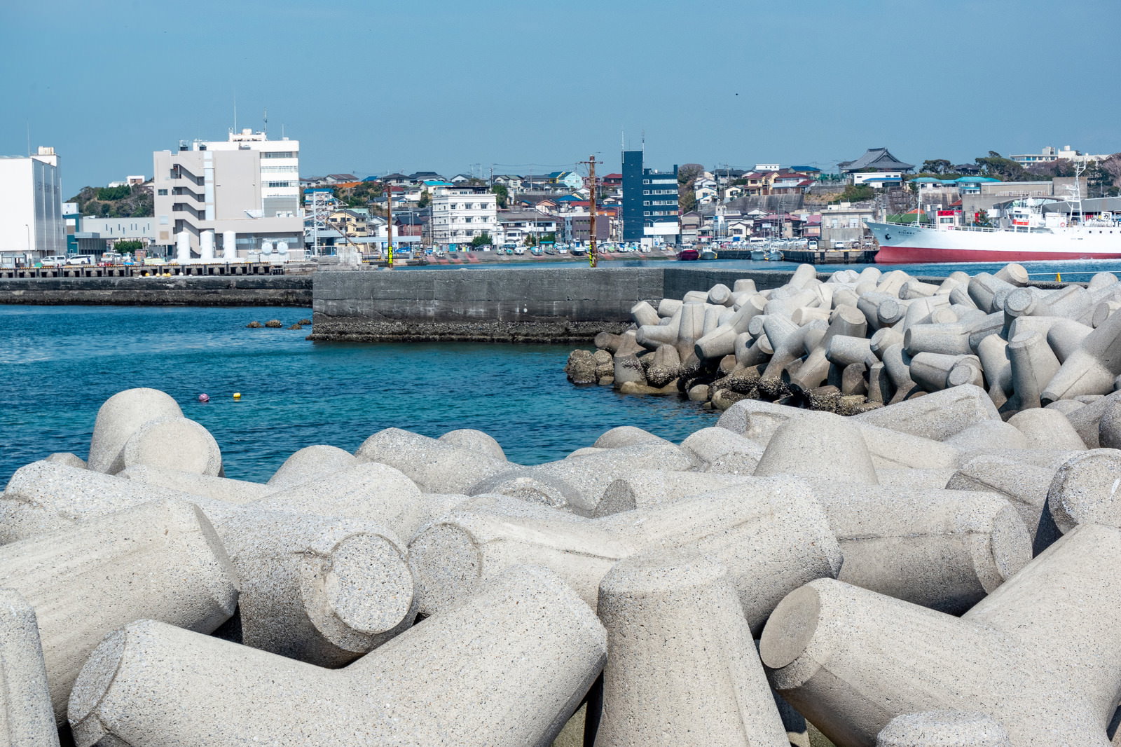 海岸に設置された白いテトラポッドと背景に広がる港町の街並み
