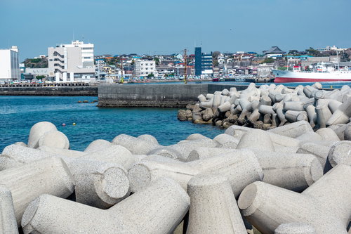 港の堤防に並ぶテトラポッドと港町の街並み