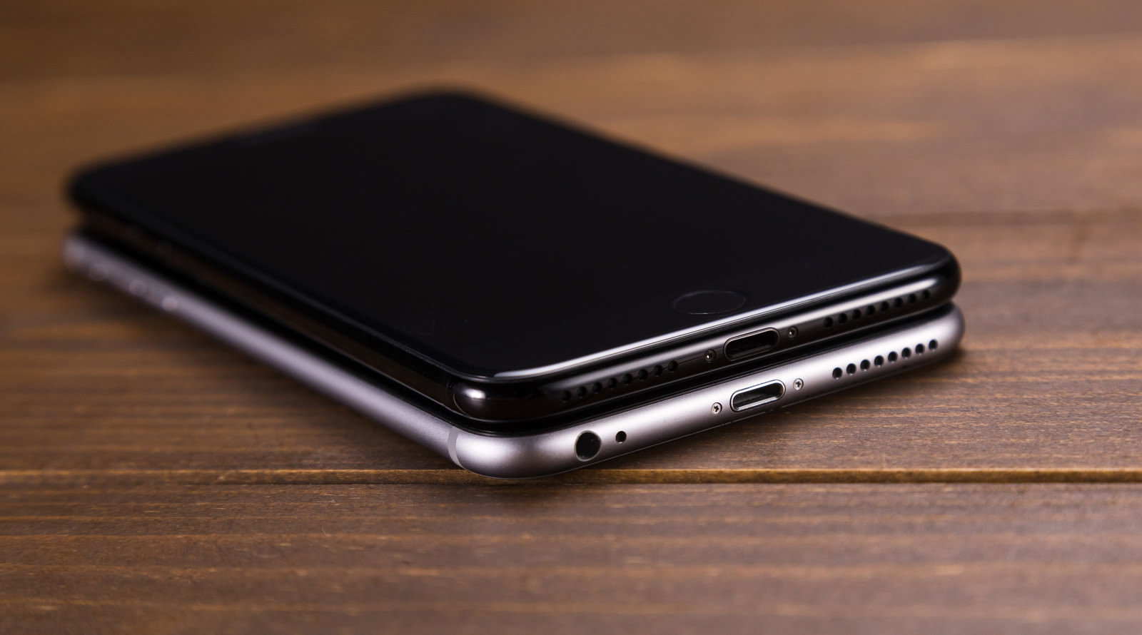 木製テーブルに重なって置かれた2台のiPhone