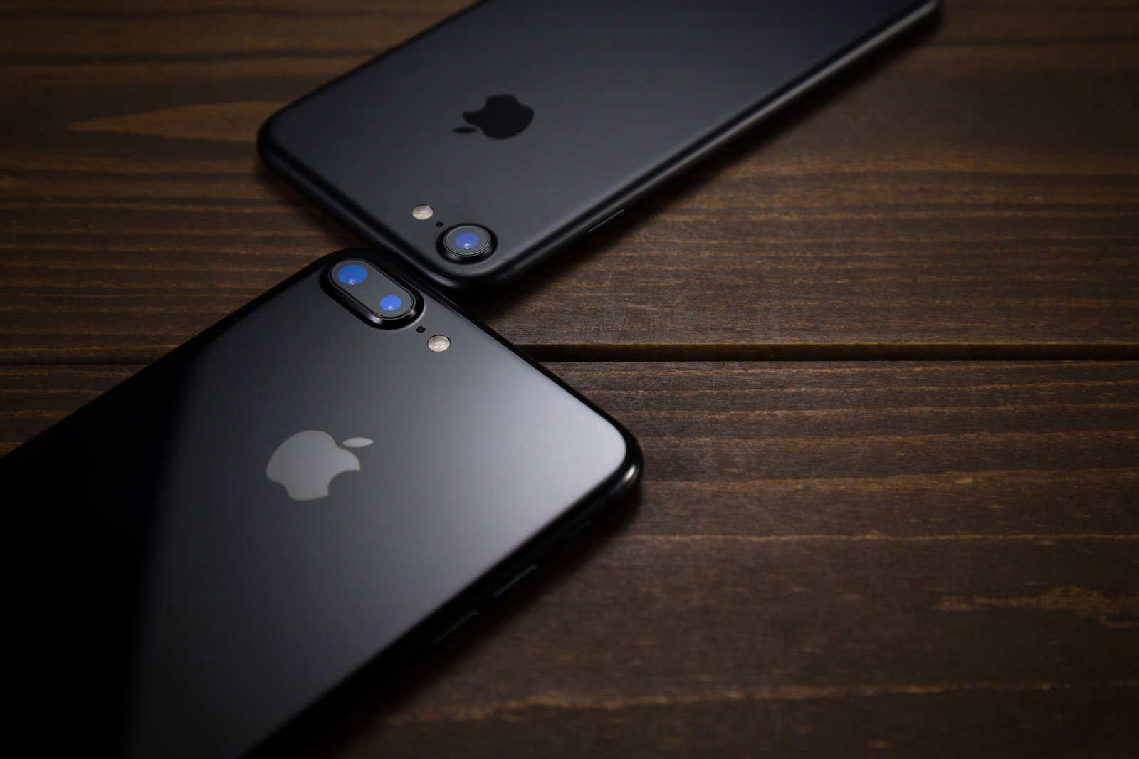 木製テーブルの上に黒いiPhoneが2台重なって置いてある