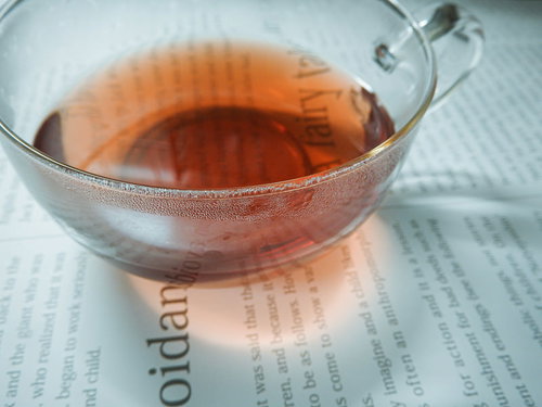 英字新聞に置かれた琥珀色の紅茶のティーカップ