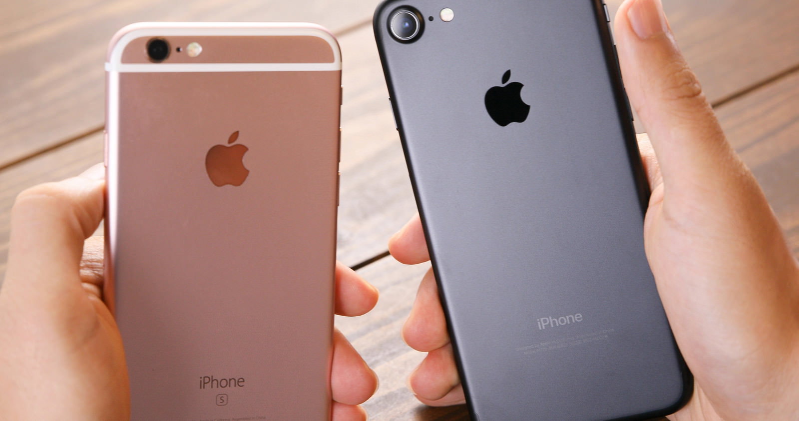 ローズゴールドと黒のiPhoneを両手で並べて持つ