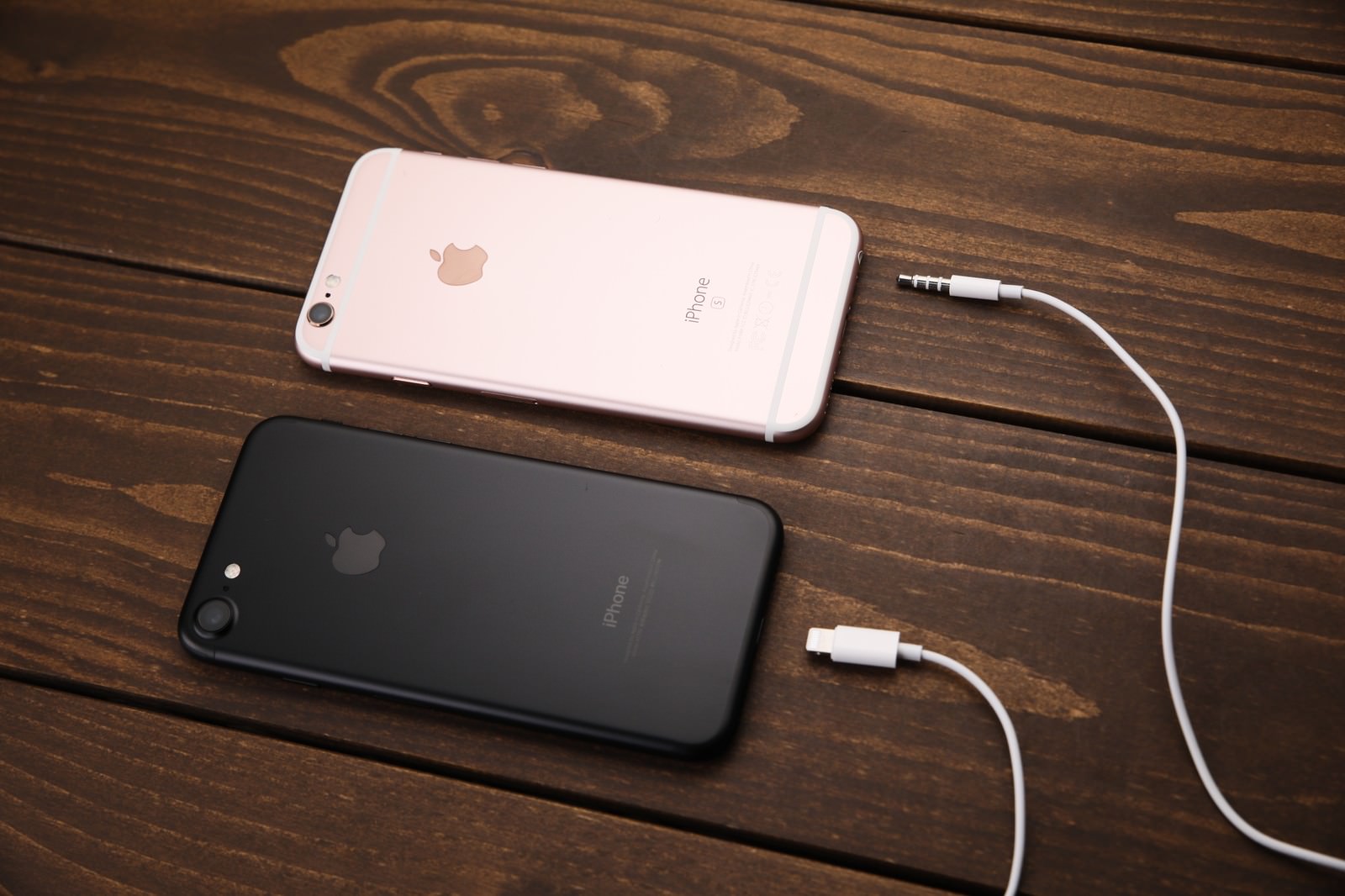 木のテーブルにiPhone 6sとiPhone 7を並べ各ケーブルを接続
