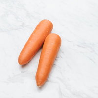 マーブル模様の白い天板に置いた2本の新鮮なにんじんの写真