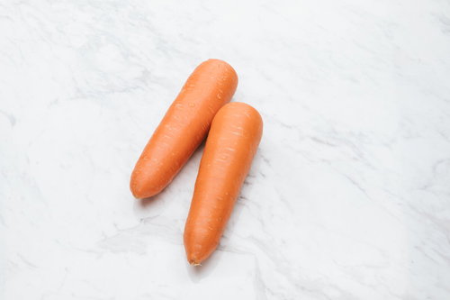 マーブル模様の白い天板に置いた2本の新鮮なにんじん