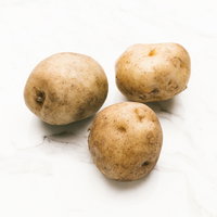 土がついた採れたてのじゃがいも3個の写真