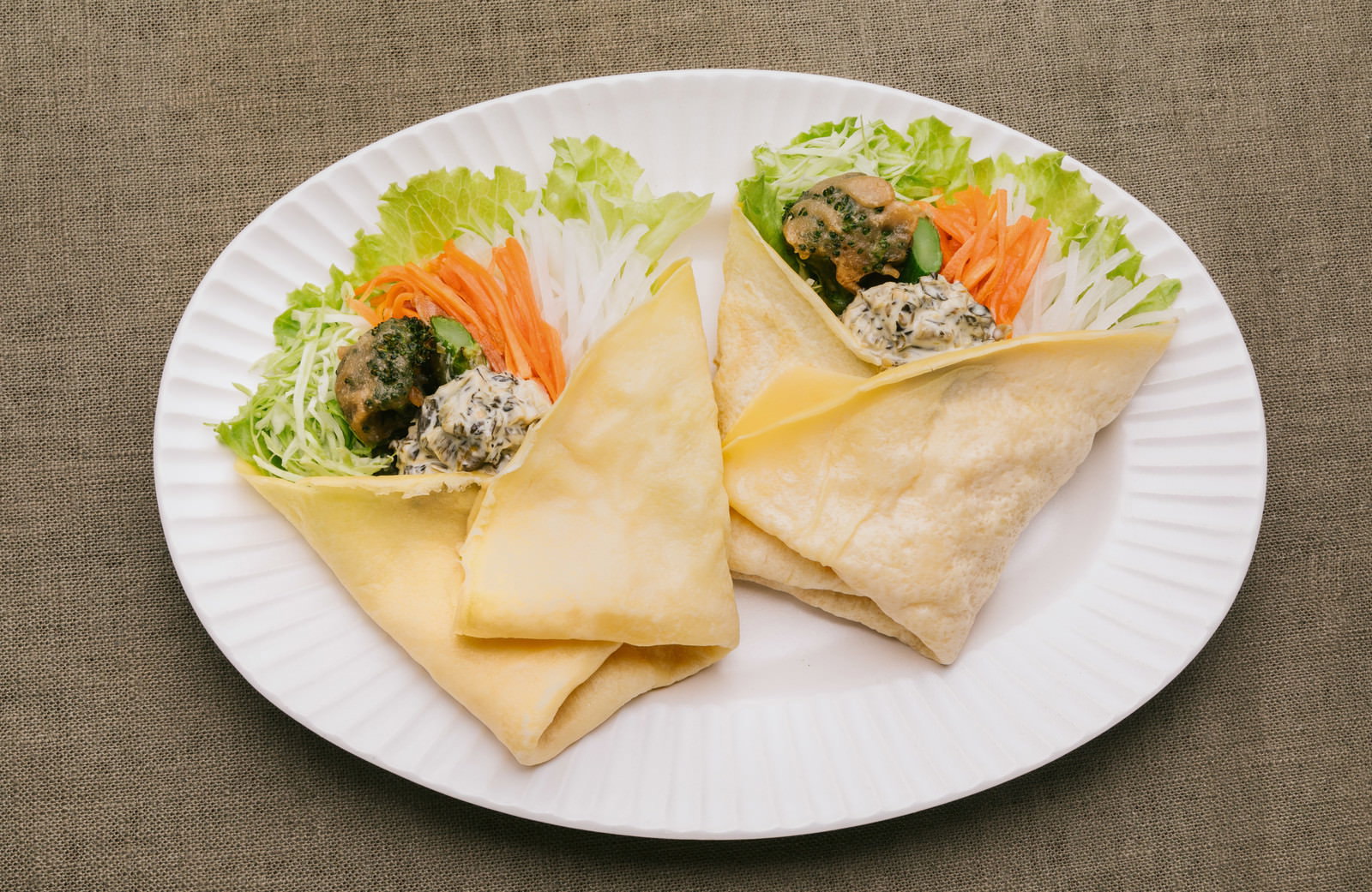 白い皿に並ぶ2本のクレープ。野菜とタルタルソースを詰めた盛り付け。