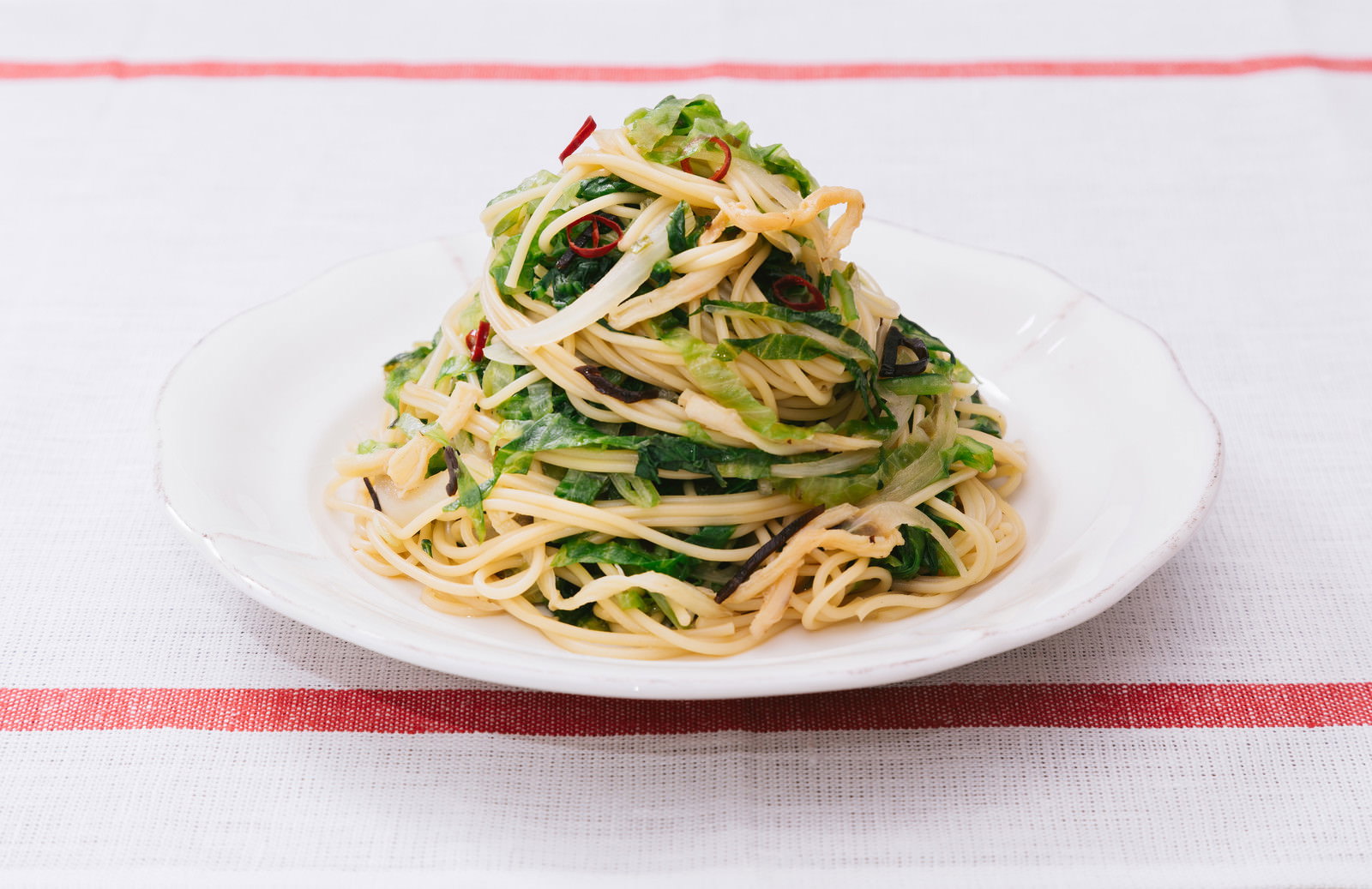 白い皿に大盛りのペペロンチーノ、葉野菜と唐辛子入り