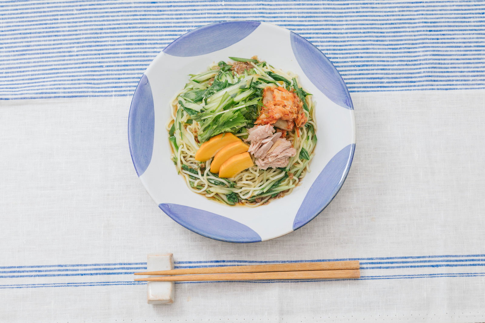 白と青の模様の皿に盛った冷やし中華。パプリカ、豚肉、錦糸卵をのせた麺料理