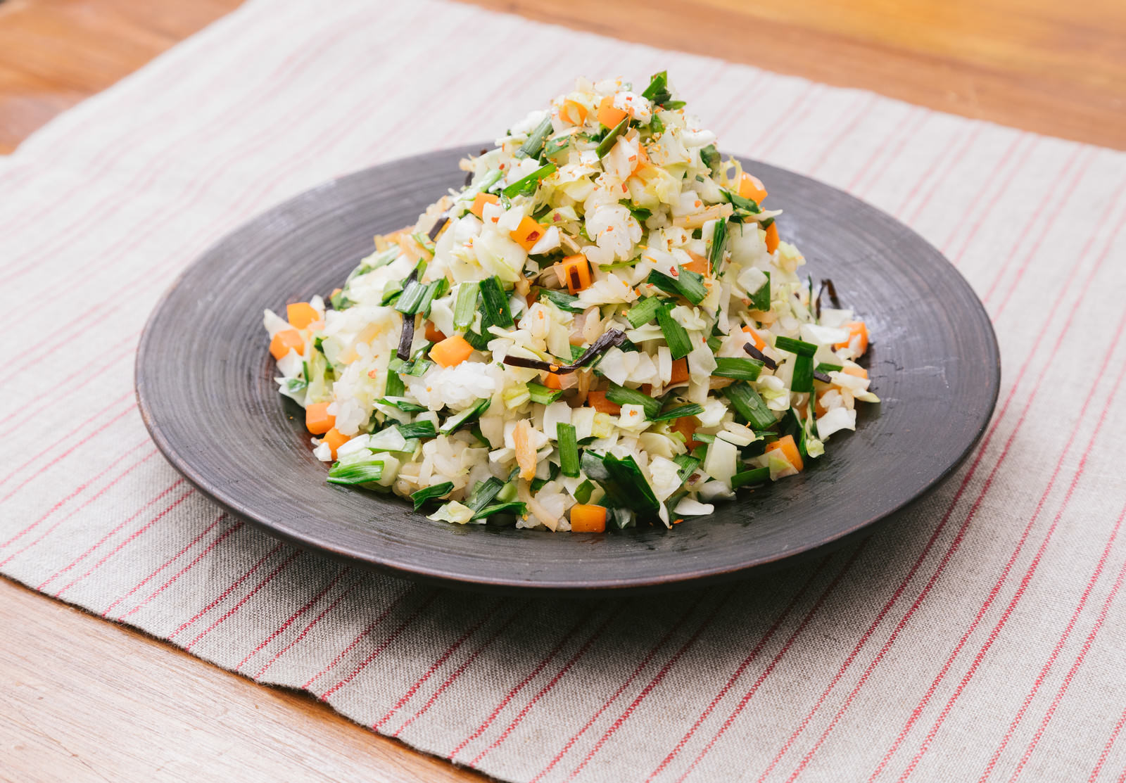 灰色の皿にのせた香味野菜入りチャーハン。長ねぎ、卵、人参、豆もやしが見える