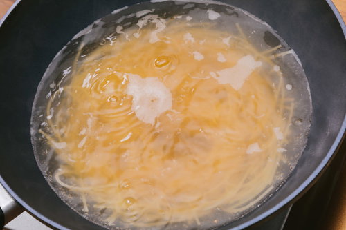 沸騰したお湯でスパゲティを茹でる調理風景