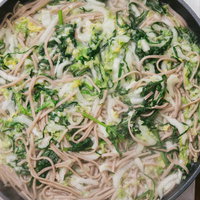 鍋にお湯を沸かしてそばと大根、白菜、ほうれん草を加えるの写真