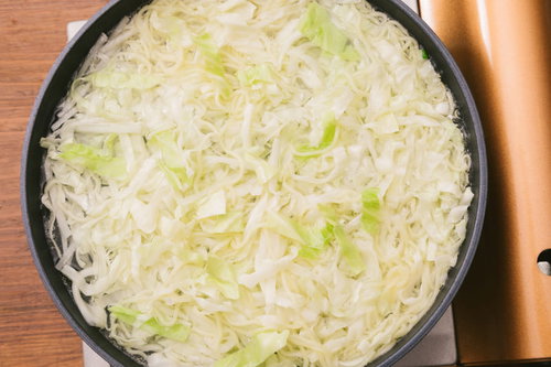 黒いフライパンで野菜を炒めるキャベツとほうれん草のひと煮立ち
