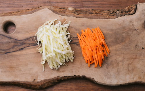木製まな板の上で千切りにしたキャベツとにんじん