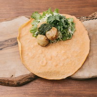 木のまな板の上でジェノベーゼソースを添えたベジクレープを調理中の写真