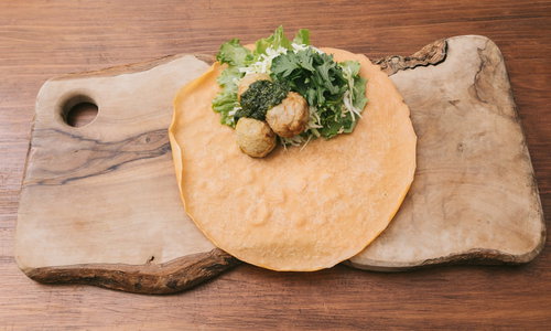 木のまな板の上でジェノベーゼソースを添えたベジクレープを調理中