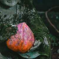 東堂山満福寺の石像が手にする桃と苔むした石像の写真