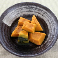 黒い和食器に盛られた角切りかぼちゃの煮物の写真