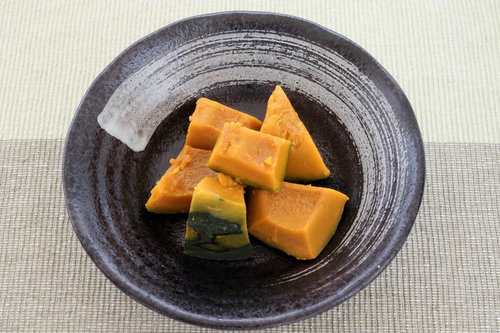 黒い和食器に盛られた角切りかぼちゃの煮物