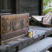 岳温泉の神社で賽銭箱前に供えられた酒瓶と参拝風景の写真
