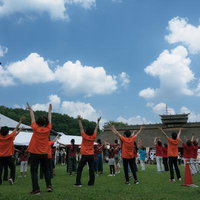 三春花火会場で両手を挙げて踊る赤いシャツの参加者たちの写真
