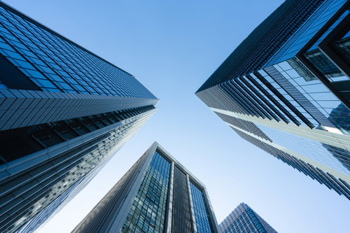 都会のビル群を見上げた視点、青空を背景にした高層ビルの建築