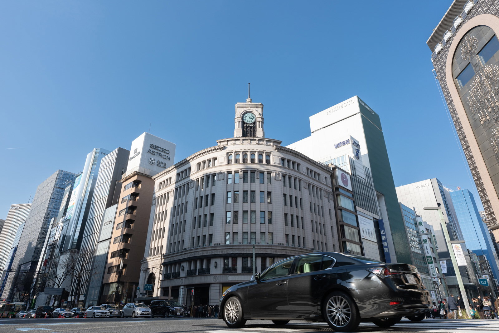 銀座和光の時計台が見える交差点に停まる黒い高級車