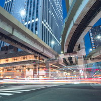 首都高下の交差点に映る光跡：夜間の車両が描く光の軌跡の写真