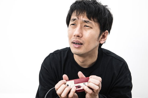 こんなコントローラーの持ち方じゃうまくプレイできないと涙目のゲーマー男性