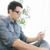 進捗状況をスマホで確認する休暇中のエンジニア男性の写真