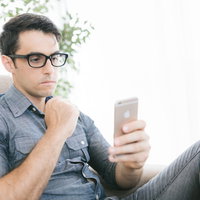 ニュースアプリを見て不安な気持ちになる眼鏡の男性の写真