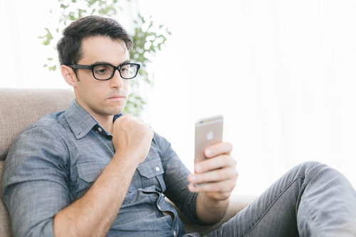 ニュースアプリを見て不安な気持ちになる眼鏡の男性