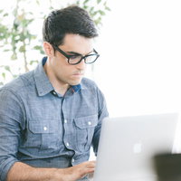 明るいオフィスでコーディング中のエンジニア男性の写真