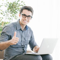 オフィスのデスクでLGTMサインを送るエンジニアのリアルの写真