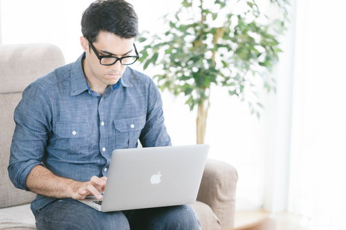 自宅のソファでノートパソコンを操作するエンジニア男性