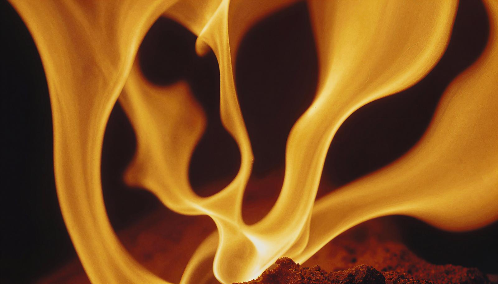 黄色と赤色が混ざり合う激しく燃える炎が黒い背景に舞い上がっている